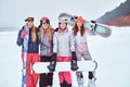 Cheerful women friends in sports winter clothes with snowboards and skis posing Royalty Free Stock Photo