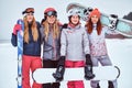 Cheerful women friends in sports winter clothes with snowboards and skis posing Royalty Free Stock Photo