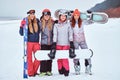 Cheerful women friends in sports winter clothes with snowboards and skis posing Royalty Free Stock Photo