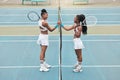 Cheerful women holding hands over the net on a tennis court. Young women support each other after tennis practice