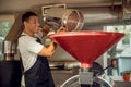 Cheerful worker pouring coffee grains into the roasting machine Royalty Free Stock Photo