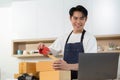E-commerce Packaging. Smiling worker sealing boxes with tape while using a laptop. Royalty Free Stock Photo