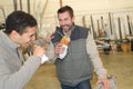 Cheerful workers having lunch eating sandwich in workshop Royalty Free Stock Photo