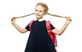 Cheerful 8 years old schoolgirl with backpack wearing uniform standing isolated over white background. Ready for school