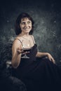 Cheerful 40 years old woman in classic dress with glass of wine Royalty Free Stock Photo