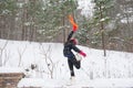 Cheerful young adult wearing a black jacket is happily jumping and striking a pose