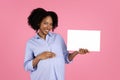 Cheerful young african american curly woman with big belly show banner with free space, enjoy pregnant