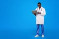 Cheerful young african american guy doctor in white coat, glasses uses laptop to chat with patient