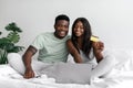 Cheerful young african american husband and wife looking at laptop and showing credit card, shopping online Royalty Free Stock Photo