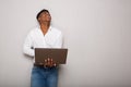 Cheerful young African american man holding laptop and looking up by gray background Royalty Free Stock Photo