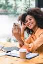 Cheerful young African American pretty woman, entrepreneur in casual wear, smiling, using smartphone in a modern office. Royalty Free Stock Photo