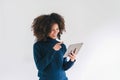 Cheerful young African American pretty woman, entrepreneur in casual wear, smiling, using tablet in a modern office. Royalty Free Stock Photo