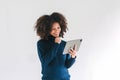 Cheerful young African American pretty woman, entrepreneur in casual wear, smiling, using tablet in a modern office. Royalty Free Stock Photo