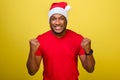 An African-American man in a red T-shirt and a Christmas hat makes a gesture with clenched fists and says YES Royalty Free Stock Photo