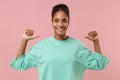 Cheerful young african american woman girl in green sweatshirt posing isolated on pastel pink wall background studio Royalty Free Stock Photo