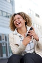 Cheerful young african american woman laughing outside with cellphone Royalty Free Stock Photo