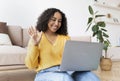 Cheerful young African American woman making video call on laptop at home, waving at webcam Royalty Free Stock Photo