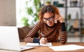 Cheerful young african american woman talking someone on mobile phone while working remotely or studying online from home Royalty Free Stock Photo