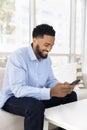Cheerful young African man chatting on mobile phone, typing message Royalty Free Stock Photo