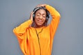 Cheerful young african woman listening to music with headphones isolated over grey background, dancing Royalty Free Stock Photo