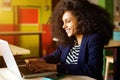 Cheerful young african woman using laptop at coffee shop