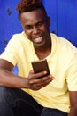 Cheerful young afro american man sitting outside and using mobile phone Royalty Free Stock Photo