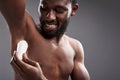 Joyful handsome afro American man using his deodorant