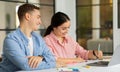 Cheerful young arab lady and european man manager work with documents and laptop, planning finance