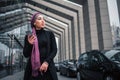 Cheerful young arabian model stand outside and pose. Woman hold phone and look to right. She stands close to black cars.