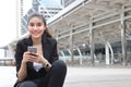 Cheerful young Asian business woman with mobile smart phone in urban background. Royalty Free Stock Photo