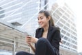 Cheerful young Asian business woman with mobile smart phone in urban background. Internet of things concept. Royalty Free Stock Photo