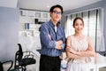 Cheerful young Asian businessman wearing eyeglasses and a businesswoman in casual smiling and looking at the camera while standing Royalty Free Stock Photo