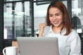 Cheerful young Asian businesswoman with laptop having ideas in office. Thinking and thoughtful business concept. Royalty Free Stock Photo