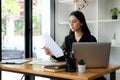 Cheerful young asian female entrepreneur sitting in bright modern office and working with computer laptop Royalty Free Stock Photo