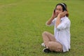 Cheerful young asian man listening to music with headphone in green grass with copy space background. Royalty Free Stock Photo