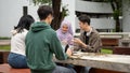 A cheerful Asian-Muslim female college student is doing homework or a group project with her friends Royalty Free Stock Photo