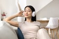 Cheerful young Asian student girl relaxing with favorite ambient tunes