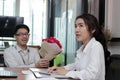 Cheerful young Asian woman accepting a bouquet of red roses from boyfriend in office on valentine`s day. Love and romance in work Royalty Free Stock Photo