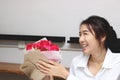 Cheerful young Asian woman accepting a bouquet of red roses from boyfriend in office on valentine`s day. Love and romance in work Royalty Free Stock Photo