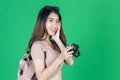 Cheerful young Asian woman with bag and digital camera ready enjoy travel over green isolated background Royalty Free Stock Photo