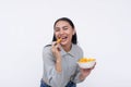 A cheerful young asian woman enjoying a bowl of cheese puffs. Having a delicious snack. Isolated on a white background Royalty Free Stock Photo