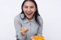 A cheerful young asian woman enjoying a bowl of cheese puffs. Having a delicious snack. Isolated on a white background Royalty Free Stock Photo