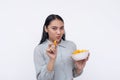 A cheerful young asian woman enjoying a bowl of cheese puffs. Having a delicious snack. Isolated on a white background Royalty Free Stock Photo