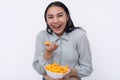 A cheerful young asian woman enjoying a bowl of cheese puffs. Having a delicious snack. Isolated on a white background Royalty Free Stock Photo