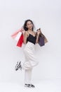 A cheerful young asian woman holding many shopping bags, enjoying a shopping spree. Isolated on a white background Royalty Free Stock Photo