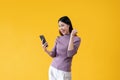 A cheerful Asian woman is showing clenched fist and looking at her smartphone with a happy face Royalty Free Stock Photo