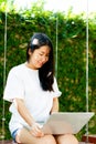 Asian woman smiling while working on her laptop outside the office, at home, working in the park. work holiday at Royalty Free Stock Photo