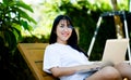 Asian woman smiling while working on her laptop outside the office, at home, working in the park. work holiday at Royalty Free Stock Photo