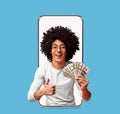 Cheerful young attractive multiracial curly guy show many dollars and thumb up on blank screen of big phone