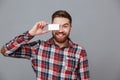 Cheerful young bearded man holding copyspace business card Royalty Free Stock Photo